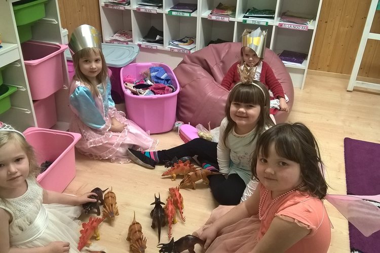Neljä tyttöä leikkimässä dinosauruksilla.