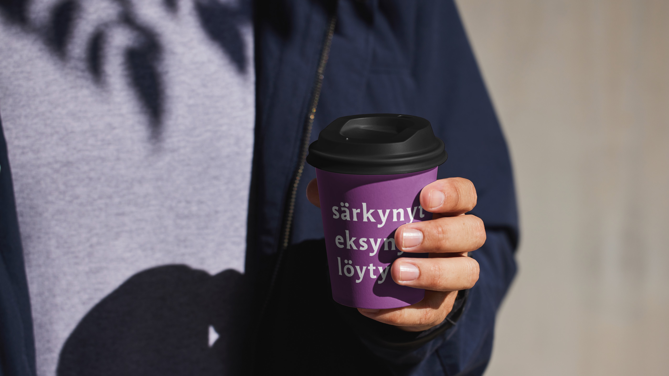 Henkilöllä kädessä violetti vaalikahvimuki.